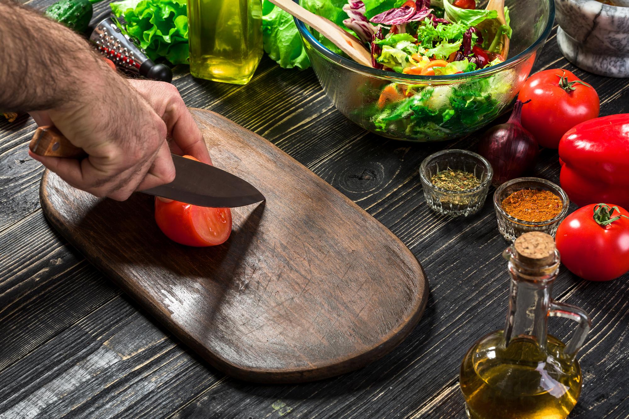Chef che affetta ingredienti su tagliere di legno